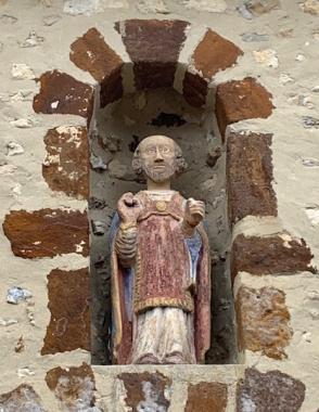 Statue de Saint Pierre en pierre polychrome dans sa niche, au-dessus de la porte romane